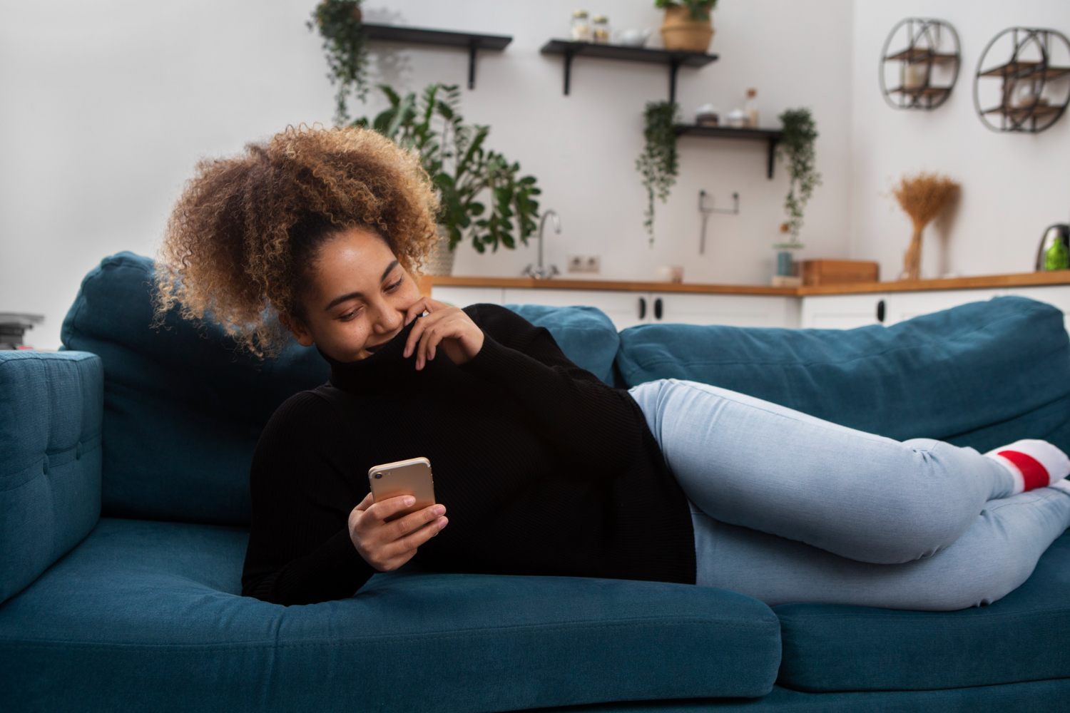 A woman relaxing on a couch, browsing on her phone